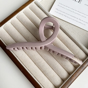 Detail of matte pink purple hair claw clip with golden logo lettering on fabric tray