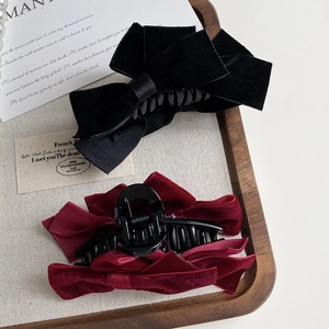 Elegant velvet double bow shark hair clips in black and burgundy on a wooden tray