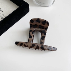 Macro detail of glossy leopard print shark hair clip with brown and black tortoiseshell texture