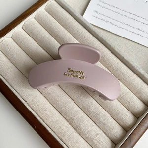 Detail of matte rose pink claw clip with golden French lettering in display box
