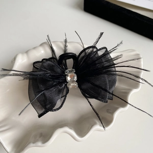 Detailed macro view of black mesh bow hair claw clip with feathers and crystals