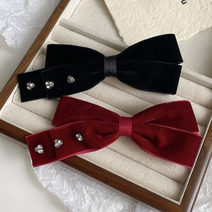 Detail of velvet bow hair clips in black and wine red with sparkling heart rhinestones