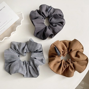 Détail de chouchous en tissu coton gris, rayé et marron avec des étiquettes tissées
