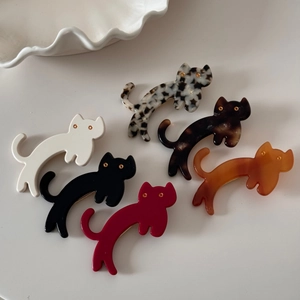 Flat lay showing six colorful acetate cat hair clips in various patterns on a ceramic plate