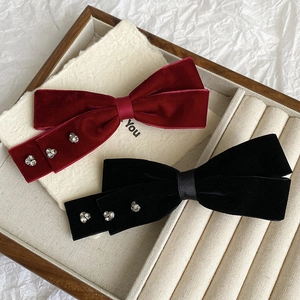 Detail of burgundy and black velvet bow hair clips with heart-shaped rhinestone accents