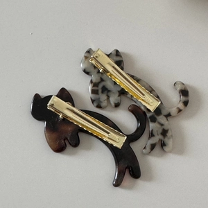 Detail showing gold metal clips and acetate texture on back of cat hair clips