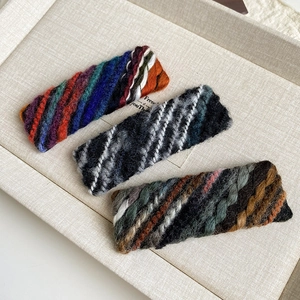 Detailed macro view of three multi-colored knitted yarn bobby pins with woven texture