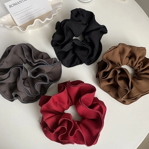 Détail de quatre chouchous en tissu à volants en noir, marron, café et rouge foncé