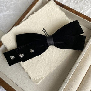 Close-up of black velvet bow hair clip with sparkling rhinestone flower detailing