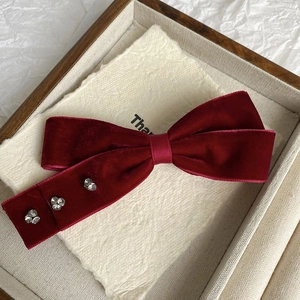 Macro view of burgundy velvet bow hair clip with sparkling rhinestone flower details
