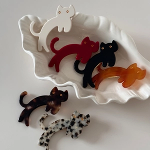 Detail of cute acetate cat hair clips in six colors on a white shell plate