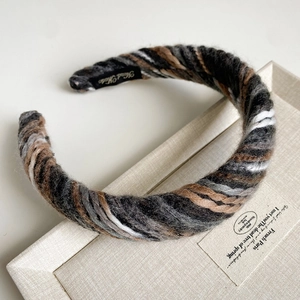 Detail of colorful chunky knit headband with Hand Made label on a soft display tray