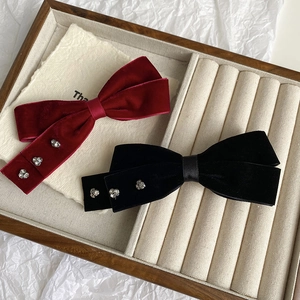 Close-up detail of velvet bow hair clips with rhinestone accents on a display tray