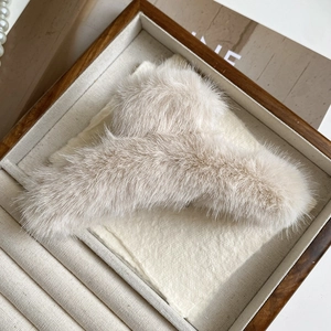 Primo piano della molletta per capelli in pelliccia di visone beige nel vassoio in legno