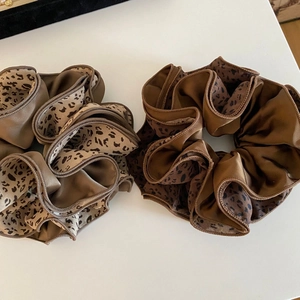 Vue détaillée de chouchous en satin à motif léopard en marron foncé et camel clair