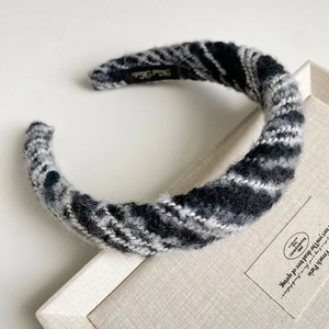 Detail shot of a handmade thick knitted headband featuring soft wool texture and black woven label