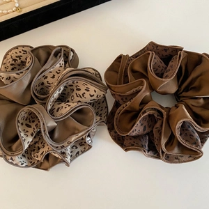 Lot de deux grands chouchous en satin à motif léopard pour coiffures sur fond beige