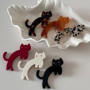 Close-up of cat-shaped acetate hair clips in various colors displayed on a white plate