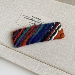 Detailed view of the colorful knitted texture and retro striped pattern on the hair clip