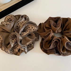 Détail de chouchous en satin à motif léopard avec un fini brillant et des bords raffinés