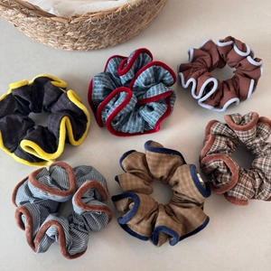 Flat lay of checkered and striped fabric scrunchies with elegant plush edge detailing