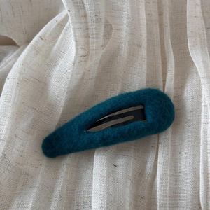 Détail d'une barrette goutte en fausse fourrure vert foncé sur un support en tissu