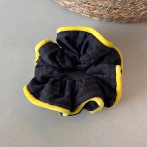 Detail view of plaid fabric scrunchie with yellow fleece trim and elastic texture