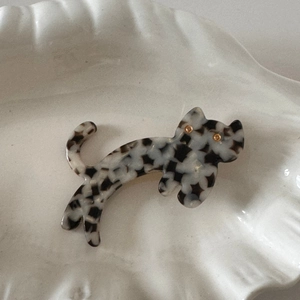 Close-up of a cat-shaped acetate hair clip with black and white marble pattern on a tray