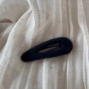 Détail de la texture en feutre noir et de la pince en métal pour cet accessoire de cheveux d'automne