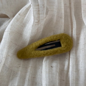 Détail de la texture en feutre de laine sur une pince à cheveux goutte vert olive