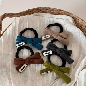 Cinq chouchous nœuds en tricot de couleurs assorties avec étiquette Nice dans un panier