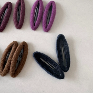 Detail view of oval wool felt snap hair clips in purple, brown and navy blue colors