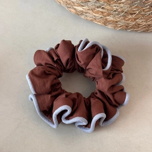 Detail of dark brown fabric scrunchie with contrast grey trim and soft pleats