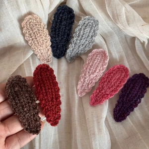 Macro detail of hand-knitted wool drop BB clips with wavy edges in eight assorted colors