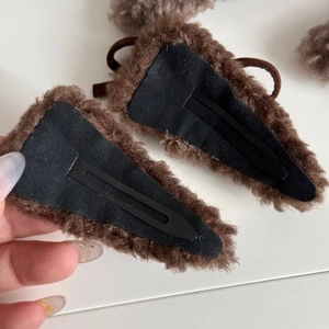 Detail view of brown plush bear ear hair clip with a secure black metal spring clasp