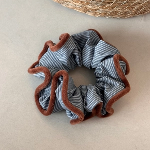 Detailed close-up of a blue striped fabric scrunchie with plush brown velvet piping edges
