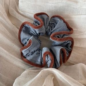 Detail of blue striped fabric scrunchie with soft brown plush trim on cotton background