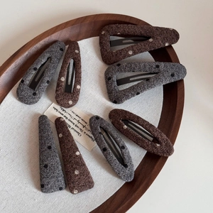Polka dot knitted wool BB hair clips in coffee and dark grey on a wooden tray