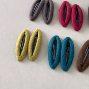 Macro shot of colorful oval felt fabric BB hair clips with textured woolen finish