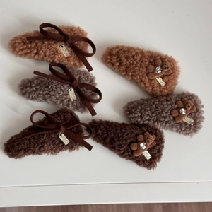 Detailed macro view of plush teddy bear hair clips with bows and golden metal tags