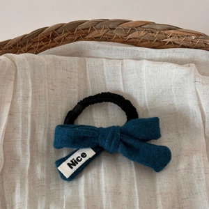 Détail de l'élastique à nœud en laine bleue avec étiquette Nice sur lin et panier