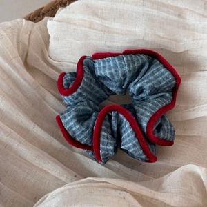 Detail of blue-grey plaid fabric scrunchie with contrasting red velvet piping edge