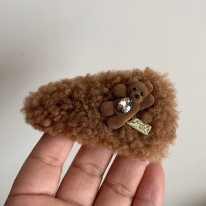 Macro detail of brown plush teddy bear hair clip with rhinestone and metal tag