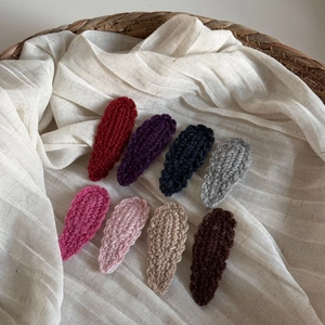 Close-up of eight colorful wavy wool knit BB hair clips on natural linen fabric