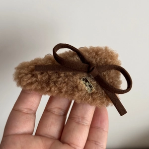 Close-up of a brown plush bear hair clip with a suede bow and golden metal detail
