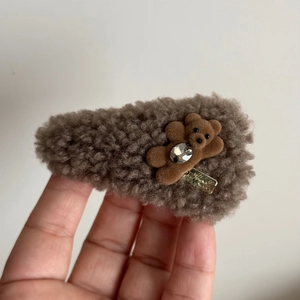 Detail of brown plush bear hair clip with sparkling rhinestone and golden tag