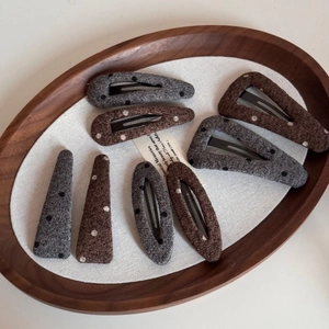 Detailed close-up of eight polka dot wool felt hair clips in brown and grey tones