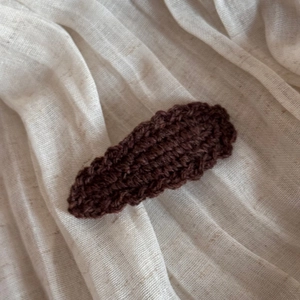 Macro detail of wave-edged handmade wool knit hair clip in dark brown coffee color