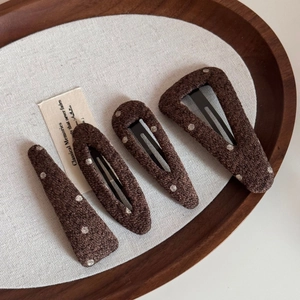 Close-up of four brown polka dot hair clips with wool texture on a wooden tray