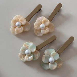 Detailed close-up of acetate flower hair clips with marble texture and pearl centers
